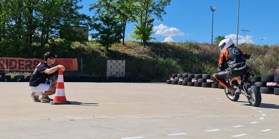 alumno entrenando tecnicas de pilotaje en moto en zona segura con instructor dandole pautas por intercomunicador