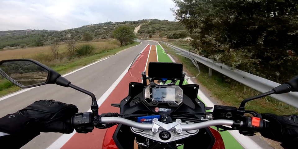 Vista onboard desde una moto mostrando el carril de la carretera dividido visualmente en tres zonas (interior, centro y exterior) para explicar la regla de los tercios y el ángulo de ataque ideal en curva.