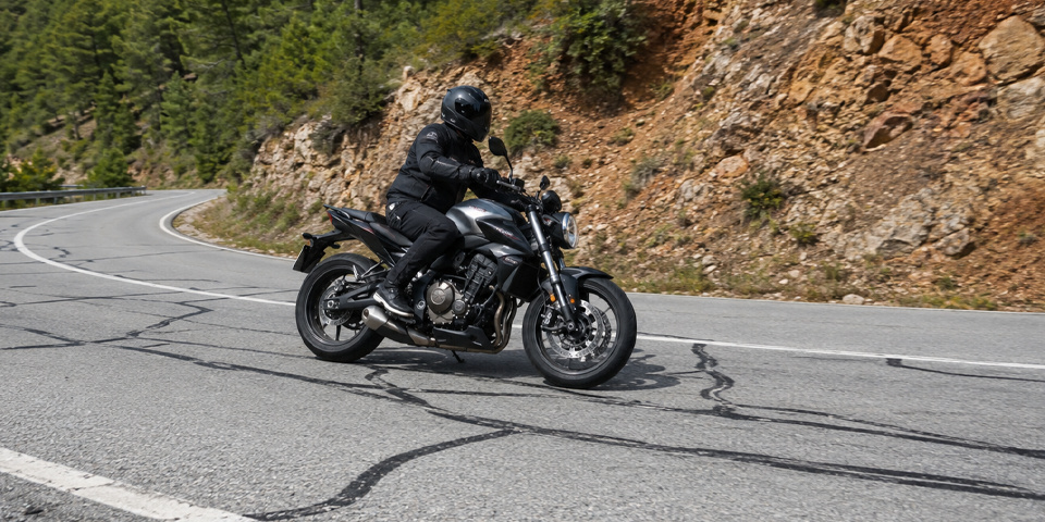 motorista pasando por líneas de alquitrán en carretera de montaña